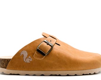 May include: Tan leather clog with a buckle closure and a cork sole. The clog has an embroidered squirrel design on the side.