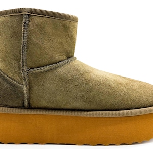 Könnte beinhalten: Ein Paar braune Wildlederstiefel mit einer dicken, orangefarbenen Plateau-Sohle. Die Stiefel haben einen umgeschlagenen Schaft und ein weiches, flauschiges Futter.