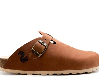 May include: Brown leather clog with a buckle closure and a cork sole. The clog has a squirrel logo on the side.