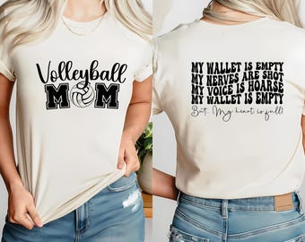 Pode incluir: Camiseta branca com texto preto que diz "Volleyball MOM" e um gráfico de voleibol. A parte de trás da camiseta diz "Minha carteira está vazia, Meus nervos estão à flor da pele, Minha voz está rouca, Minha carteira está vazia, Mas... Meu coração está cheio!"