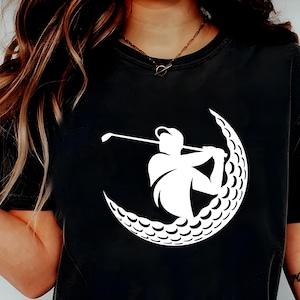 May include: Black t-shirt with a white graphic of a golfer swinging a club inside a golf ball.