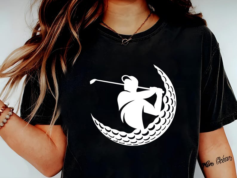 May include: Black t-shirt with a white graphic of a golfer swinging a club inside a golf ball.