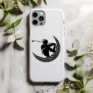 May include: White iPhone case with a black silhouette of a golfer swinging a club inside a crescent moon shape made of golf balls.