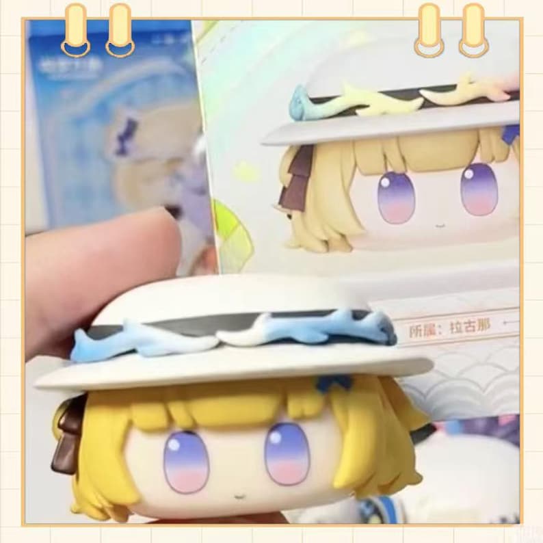 May include: A collectible figurine of a character with blonde hair, blue eyes, and a white hat with blue accents. The figurine is in a box with Japanese text. The character has a cute, cartoonish design.