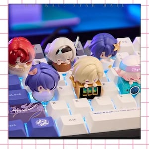 Może przedstawiać: Kolekcja kolorowych nakładek na klawisze w stylu anime, każda z unikalnym projektem postaci. Nakładki są umieszczone na białej klawiaturze z niebieskim podświetleniem. Tekst "KAI: STAR RAIL" jest widoczny u góry.