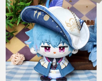 May include: A plush doll with light blue hair and a matching hat. The doll has pink eyes and is wearing a blue and white outfit with gold accents. The hat has a white brim and a blue top with gold designs. The word "MAKE" is visible.