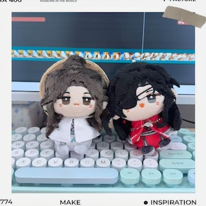 May include: Two plush dolls with detailed facial features and dark hair are displayed on a keyboard. One doll wears a white outfit, and the other is in a red and black costume. The dolls are part of a collection, possibly anime or manga-themed.