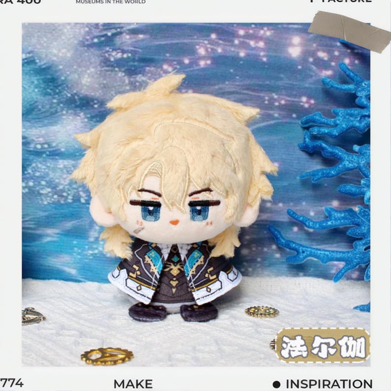 May include: A plush doll with light blonde hair and blue eyes, wearing a detailed black and gold jacket. The doll is set against a winter-themed backdrop with blue accents and the text "Inspiration".