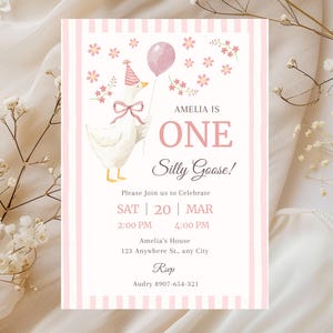 May include: A pink and white invitation card for a first birthday party. The card features a watercolor illustration of a goose wearing a party hat and holding a balloon. Text includes "Amelia is One Silly Goose!" and party details.