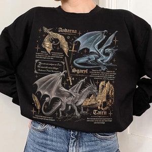 May include: Black sweatshirt with a graphic print of three dragons with gold accents and text that reads "Andarna", "Sgaeyl", and "Tairn".