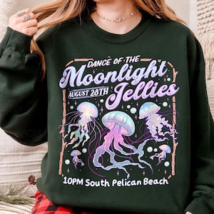 Puede incluir: Sudadera verde oscuro con un dise&ntilde;o gr&aacute;fico de medusas en tonos morados, azules y rosas. El texto dice "Dance of the Moonlight Jellies, August 28th, 10PM South Pelican Beach."