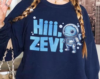 May include: Navy blue sweatshirt featuring the text "Hiii, ZEV!" in light blue, along with a cartoon astronaut character. The design is centered on the front of the sweatshirt.