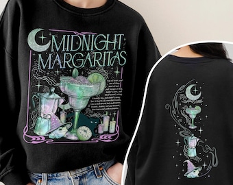 以下が含まれることがあります： 「MIDNIGHT MARGARITAS」の文字、マルガリータグラス、マキネッタ、紫の帽子をかぶったカエル、キャンドル、三日月が描かれたグラフィックプリント付きの黒いクルーネックトレーナー。背中にも同じデザインの小さなプリントが施されています。