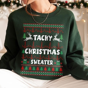 May include: Green Christmas sweater with a white design that says "Tachy Christmas Sweater" with a heart and a gift on either side of the word "Sweater". The design also includes a reindeer and a Christmas tree.