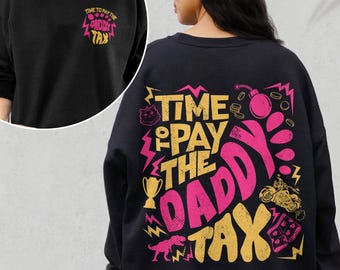 May include: A black crewneck sweatshirt featuring a small graphic on the front left chest and a large graphic on the back. Both prints display the text "TIME TO PAY THE DADDY TAX" in yellow and pink, accompanied by icons of a cat, bomb, trophy, dinosaur, and motorcycle.