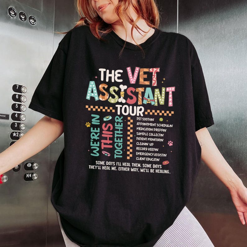 May include: A black short-sleeve t-shirt featuring a colorful graphic print that reads The Vet Assistant Tour. The design includes a list of tasks like Pet Soothing and Medication Prepping, along with the text We're In This Together and Some days I'll heal me, either way, we'll be healing.
