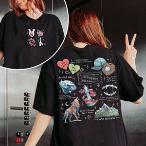 K&ouml;nnte beinhalten: Schwarzes T-Shirt mit einem grafischen Druck, der einen Wolf, eine Schachfigur, einen Diamanten, ein Herz und Text zeigt, der "Team Edward Team Jacob", "Shin Of A Killer", "I see the light, I see the door, I might never see the stars", "And the book fell in love with the beast", "I thought my enemies would never be perfect, but it is", "Death is a Peaceful Life & Hunter", "HOA HOA HOA" lautet.