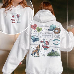 K&ouml;nnte beinhalten: Wei&szlig;er Hoodie mit einem grafischen Druck verschiedener Illustrationen, darunter ein Wolf, ein Diamant, eine Schachfigur, eine Baseballkappe, ein Baseball, eine Bergkette und Text, der "Shin Of A Killer", "Tran", "Death is Peaceful Life is Harder", "And as the days fall in line with the food", "HOA HOA HOA" und "I DECIDED AS LONG AS I MIGHT AS WELL DO IT THOROUGHLY" lautet.