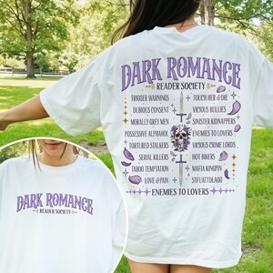 May include: White t-shirt with the text "DARK ROMANCE READER SOCIETY" in purple. The back of the shirt lists various dark romance tropes in a decorative layout, including "Trigger Warnings" and "Enemies to Lovers."