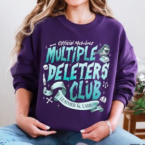 May include: Purple sweatshirt with a graphic design that says "Official Member Multiple Deleters Club Leather & Lark" with a skull, a knife, a bird, and musical notes.