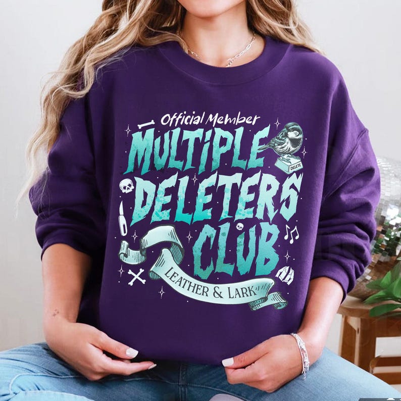 May include: Purple sweatshirt with a graphic design that says "Official Member Multiple Deleters Club Leather & Lark" with a skull, a knife, a bird, and musical notes.