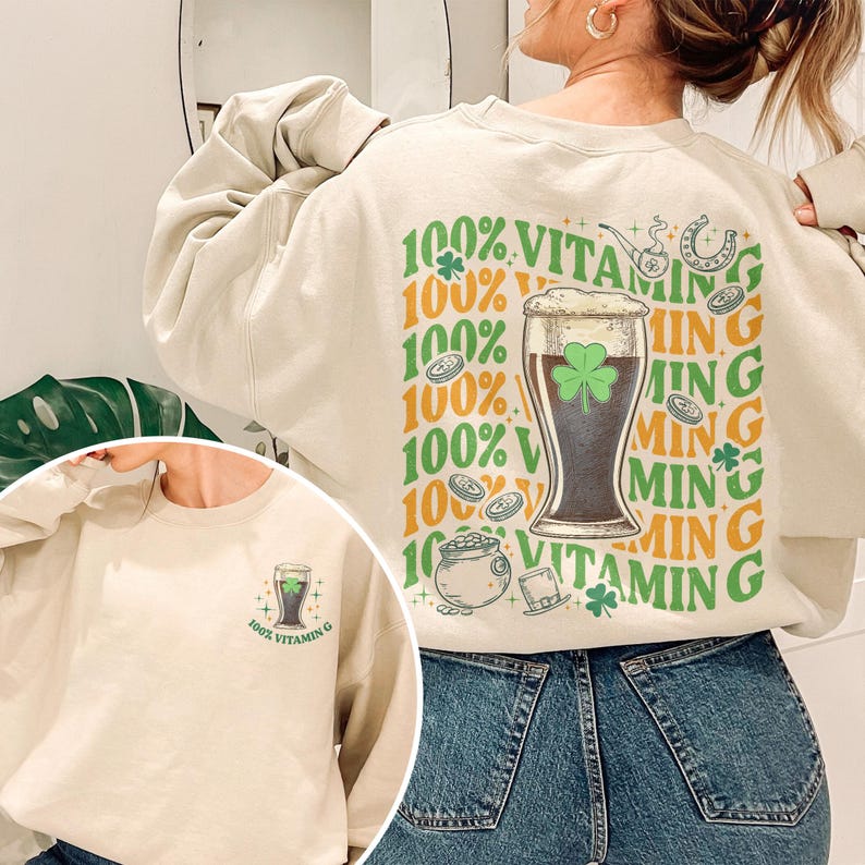 Puede incluir: Sudadera beige con tem&aacute;tica del D&iacute;a de San Patricio. La parte trasera presenta un vaso de cerveza con un tr&eacute;bol, una herradura y el texto "100% Vitamin G". La parte delantera tiene una versi&oacute;n m&aacute;s peque&ntilde;a del dise&ntilde;o.