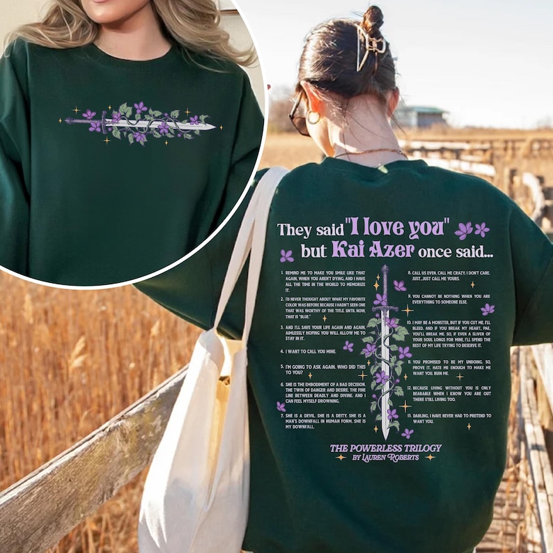 May include: Green sweatshirt with a quote from the "The Powerless Trilogy" by Lauren Roberts. The quote reads "They said "I love you" but Kai Azer once said..." and lists 12 reasons why Kai Azer loves someone. The sweatshirt features a sword with flowers and vines.