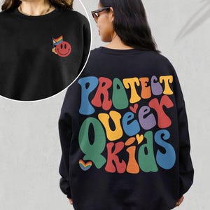 May include: Black sweatshirt with a rainbow smiley face on the front and the text "PROTECT QUEER KIDS" in rainbow letters on the back.