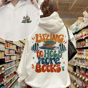 May include: White hoodie with a retro-style graphic on the back that says "Lifting to hold more books" with a stack of books and a barbell. The front of the hoodie has a small graphic of a bug lifting weights.