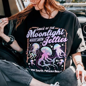 Puede incluir: Camiseta negra con un dise&ntilde;o de medusas coloridas y el texto "Dance of the Moonlight Jellies, August 28th, PM South Pelican Beach". El dise&ntilde;o presenta medusas en tonos morados, azules y rosas.