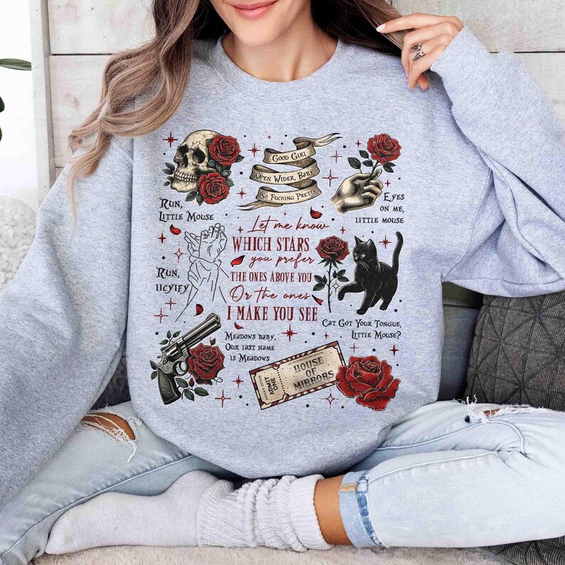 May include: Gray sweatshirt with a graphic print of red roses, a skull, a black cat, and text that reads "Let me know which stars you prefer the ones above you or the ones I make you see".