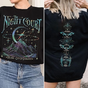 May include: Black sweatshirt with a graphic print of a crescent moon, stars, and mountains with the text "The Night Court Velaris City of Starlight". The back of the sweatshirt has a vertical graphic print of celestial symbols.