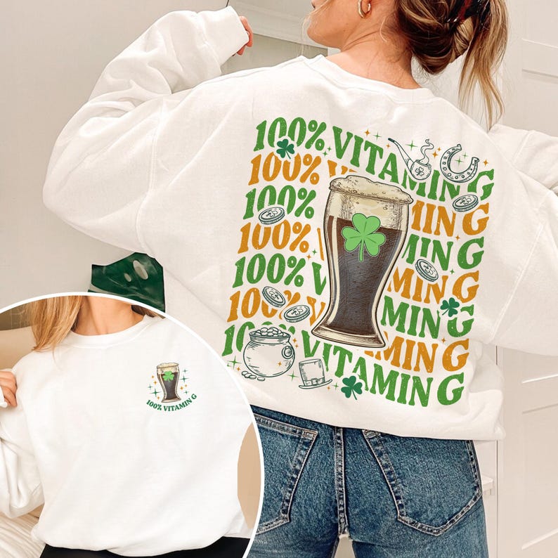 Puede incluir: Sudadera blanca con tem&aacute;tica del D&iacute;a de San Patricio. La parte trasera presenta un gr&aacute;fico de una copa de cerveza con un tr&eacute;bol, monedas y el texto "100% Vitamin G". Una versi&oacute;n m&aacute;s peque&ntilde;a del dise&ntilde;o est&aacute; en la parte delantera.