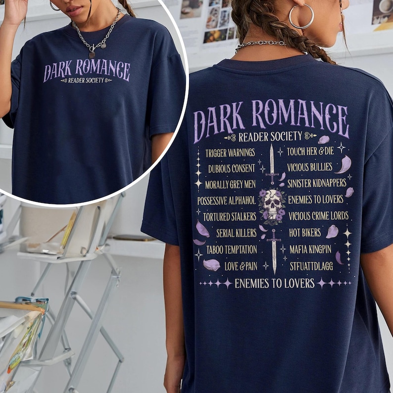 May include: Navy blue t-shirt with the text "DARK ROMANCE READER SOCIETY" in purple. The back of the shirt lists trigger warnings and other phrases in purple. A skull graphic is also visible.