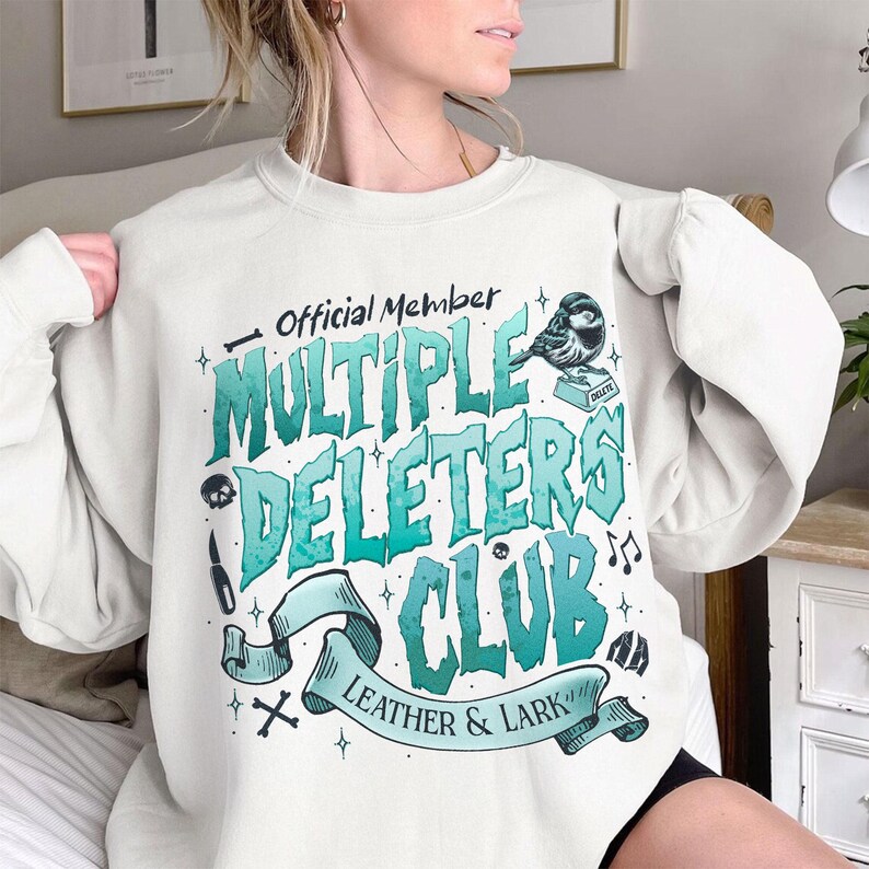 May include: White sweatshirt with a blue and green graphic design that says "Official Member Multiple Deleters Club Leather & Lark". The graphic also includes a small bird, a skull, and musical notes.