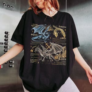 May include: Black t-shirt with a graphic print of three dragons. The dragons are named Sgaepl, Andarna, and Cairn. The text on the shirt reads: "A dragon without its rider is a shadow. A rider without their dragon is death."