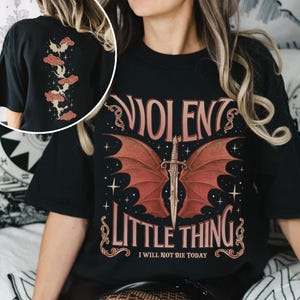 May include: Black t-shirt with a red and gold graphic of a dragon with wings and a dagger. The text "VIOLENT LITTLE THING" is above the dragon and the text "I WILL NOT DIE TODAY" is below the dragon.