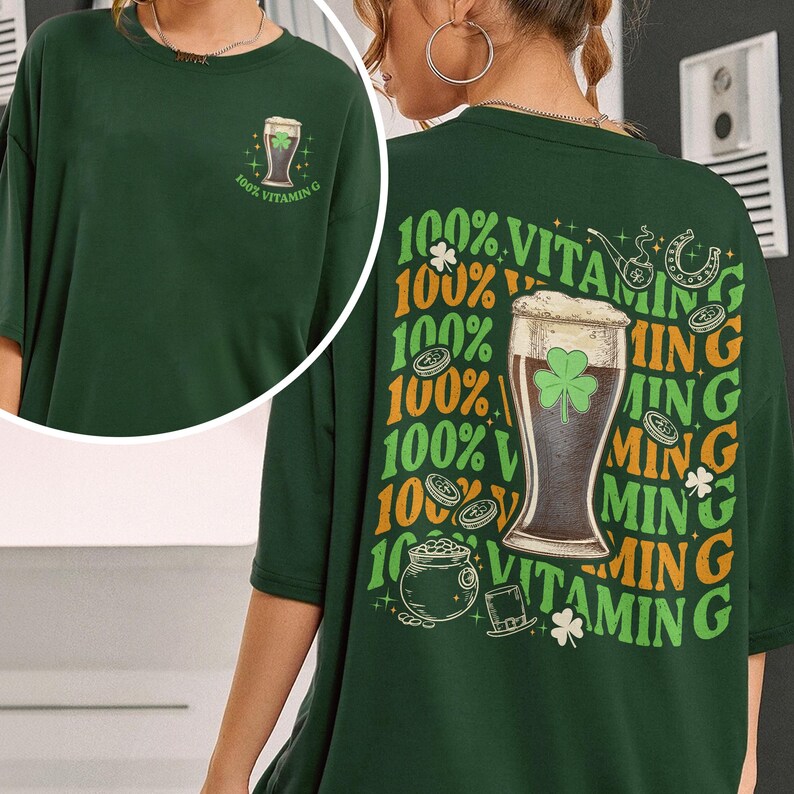 Puede incluir: Camiseta verde oscuro con tem&aacute;tica del D&iacute;a de San Patricio. La parte delantera presenta un gr&aacute;fico de vaso de cerveza con el texto "100% Vitamin G". La parte trasera muestra un dise&ntilde;o m&aacute;s grande con un vaso de cerveza, tr&eacute;boles y las palabras "100% Vitamin G."