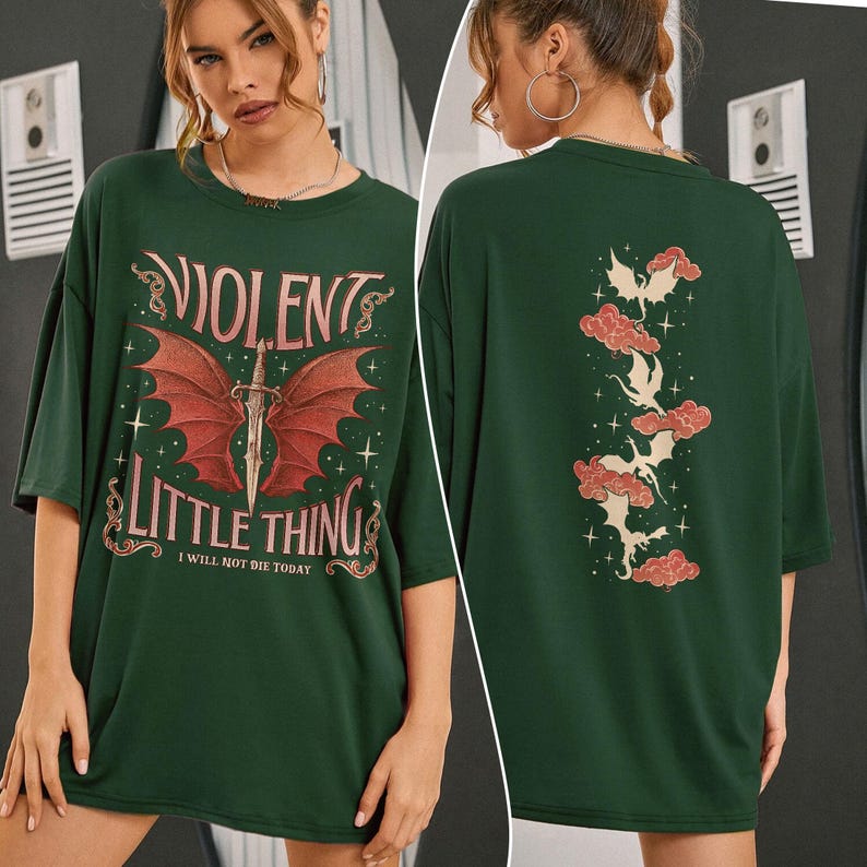 May include: A dark green oversized t-shirt with a graphic print of a winged creature and a dagger. The text "Violent Little Thing I Will Not Die Today" is printed on the front of the shirt.