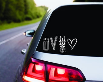 May include: White vinyl car decal featuring a salt shaker, sprig, lavender bouquet, and a heart. The decal is applied to the rear window of a silver car, with a blurred background of a road and trees.