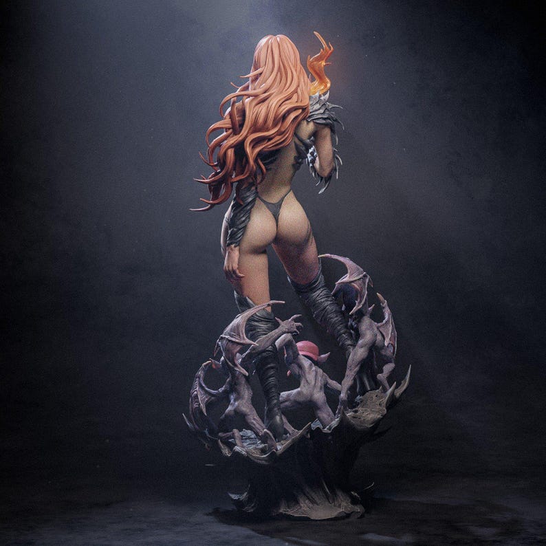 May include: A red-haired female figure with wings and a tail stands on a base with smaller figures. The figure is wearing a black and grey outfit with a flowing red cape. The base is made of a dark grey material and has a textured surface.