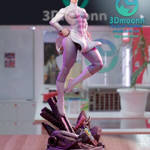 Puede incluir: Una figura de acci&oacute;n blanca y morada de una superhero&iacute;na femenina de pie sobre una base de concreto rota. La figura tiene un traje blanco y morado con una capa blanca. La figura est&aacute; en una pose de acci&oacute;n din&aacute;mica. La figura es parte de un kit de modelo impreso en 3D. El texto "3Dmoonn August reward available on my patreon" es visible en la imagen.