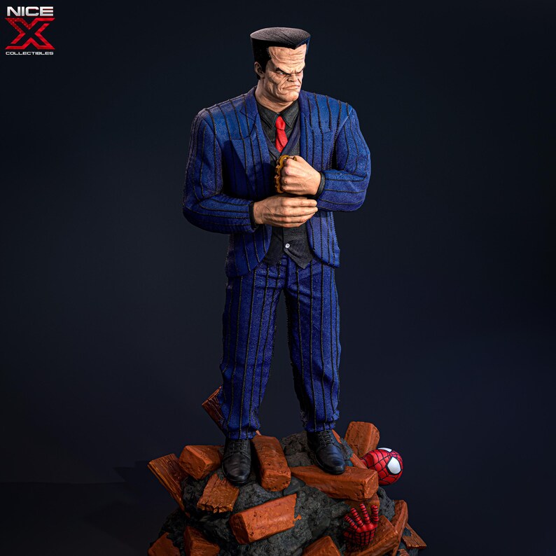 May include: A blue and black pinstripe suit figure with a bald head and a red tie. The figure is standing on a pile of broken bricks with a red and black spider figure in the background.