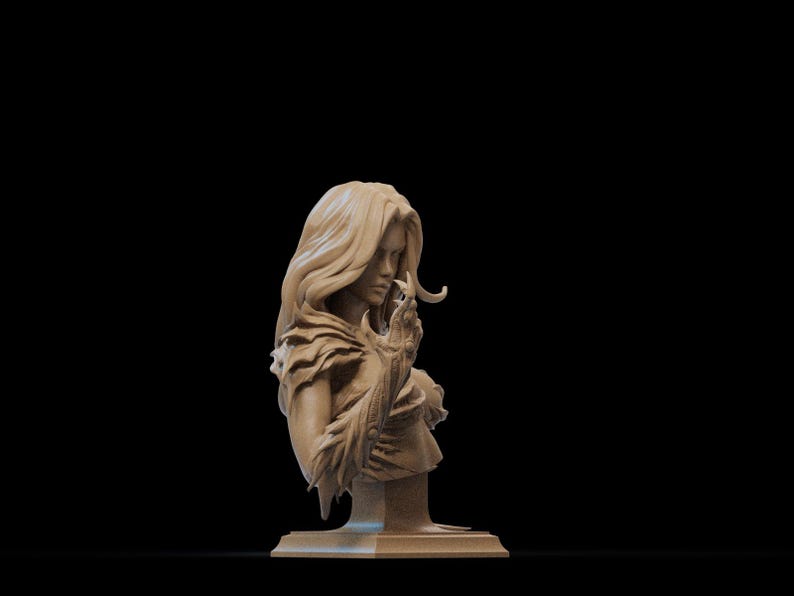 May include: A detailed bust sculpture of a woman with long flowing hair, wearing a feathered garment and holding a small object in her hand. The sculpture is made of a light brown material and is set on a square base.