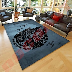 May include: A rectangular rug with a Star Wars theme. The rug features a large black and red Millennium Falcon design on a blue-grey background, with additional spaceship silhouettes. The rug is placed on a hardwood floor.