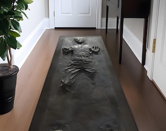May include: A black and gray doormat with a silhouette of a person frozen in carbonite. The doormat is rectangular and has a textured surface.
