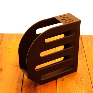 Puede incluir: Un portarevistas de madera marr&oacute;n con cuatro ranuras. El portarevistas tiene el n&uacute;mero "100" impreso en la parte delantera.