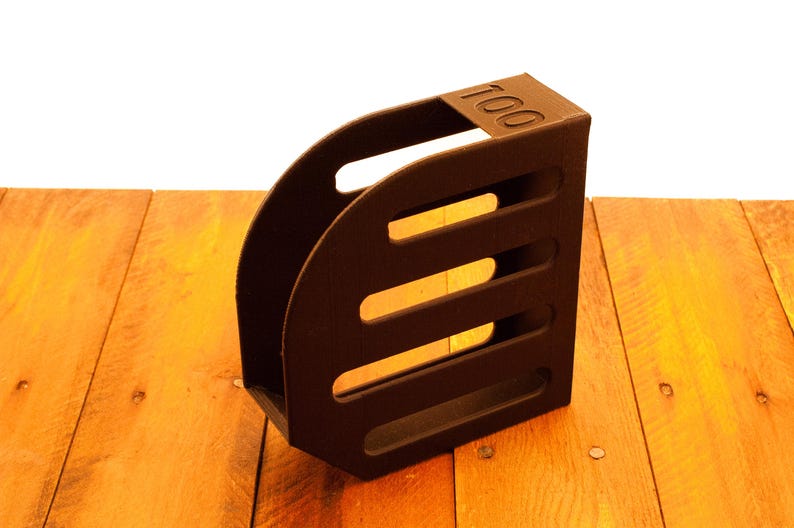 Puede incluir: Un portarevistas de madera marr&oacute;n con cuatro ranuras. El portarevistas tiene el n&uacute;mero "100" impreso en la parte delantera.