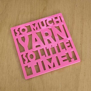 May include: Pink square coaster with the words "So Much Yarn So Little Time!" cut out.