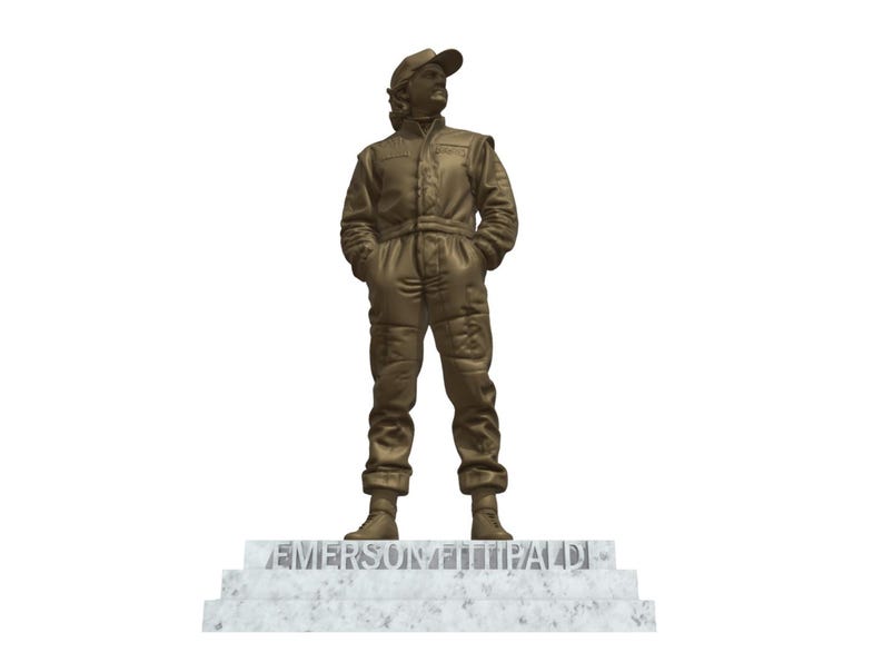 May include: A bronze statue of a person in a racing suit and cap, standing on a marble base. The statue has its hands in its pockets and is facing forward. The name "EMERSON FITTIPALDI" is inscribed on the base.